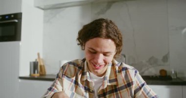 Kablosuz kulaklıklı genç adam laptoptaki bir video görüşmesinde konuşuyor.