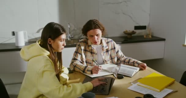 Молодая пара занимается дома с книгами и открытым ноутбуком — стоковое видео