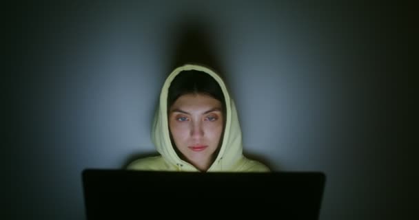 Žena sedí ve tmě na podlaze vzadu u zdi a používá notebook. — Stock video