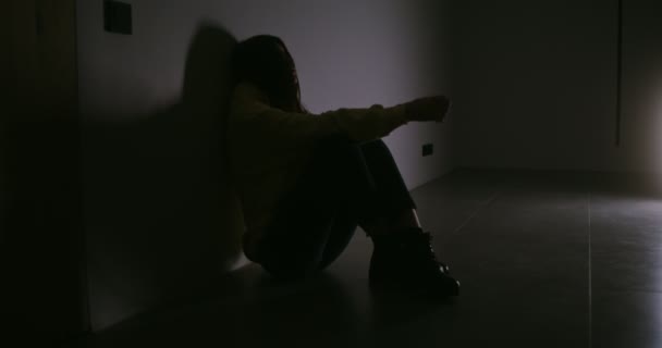 若いです動揺女性は目を閉じて暗闇の中で床に座っています — ストック動画