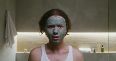 Yüzünde kilden bir maske olan genç adam kameraya bakarken gülümsüyor.