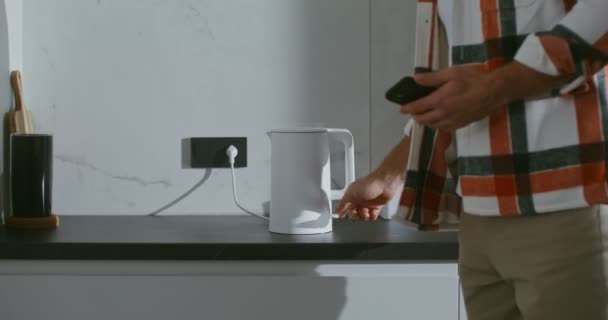 Muž obsahuje bílou varnou konvici, stojící na černém mramorovém stole — Stock video