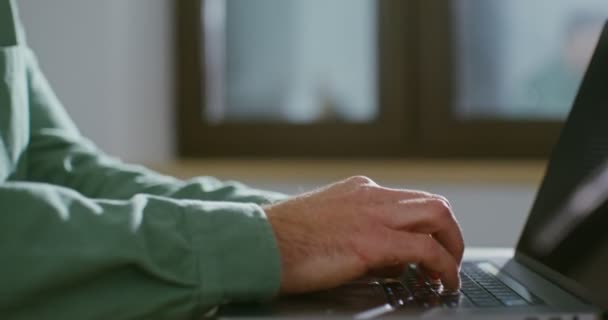 Un joven está escribiendo en un portátil con una mirada enfocada, primer plano — Vídeos de Stock