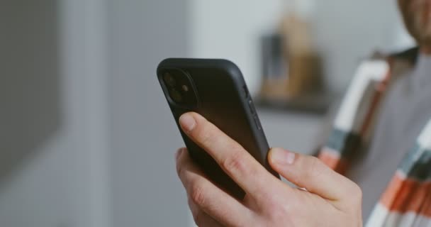 Young man drinks coffee without taking his eyes off screen of a mobile phone — Stock Video