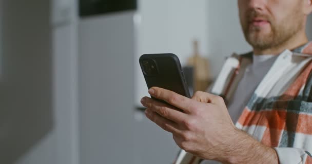 Giovane uomo beve caffè senza togliere gli occhi dallo schermo di un telefono cellulare — Video Stock