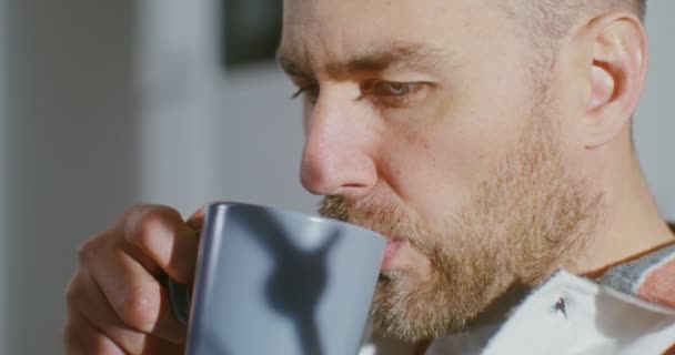 Young man drinks coffee without taking his eyes off screen of a mobile phone — Vídeo de Stock