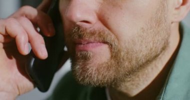 Genç adam cep telefonuna cevap veriyor, yakın plan.