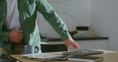 Genç bir adam mutfak masasında uzaktan kumandalı bir şekilde oturuyor.