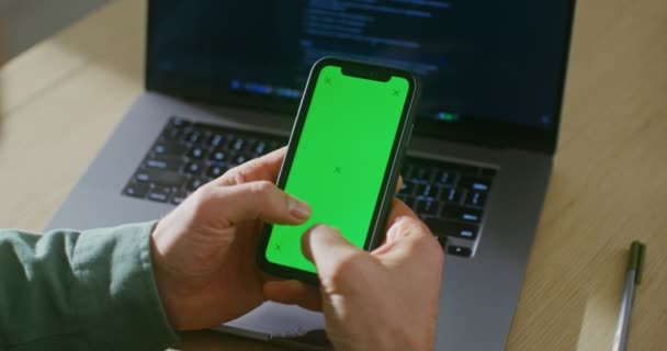En ung man skriver på en grön skärm av en mobiltelefon, kopiera utrymme — Stockvideo