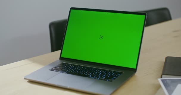 An open laptop with a green screen stands on the architects desktop — Stockvideo