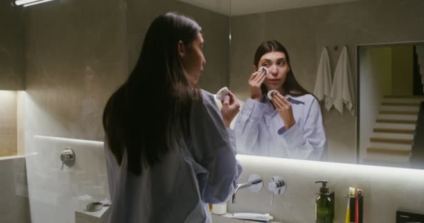 Mujer joven se frota la cara con almohadillas de algodón, elimina el maquillaje — Vídeo de stock