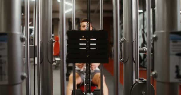 The weights of machine are lifted by the efforts of a young, athletic man — Stock Video
