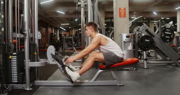 The weights of machine are lifted by the efforts of a young, athletic man — Stockvideo