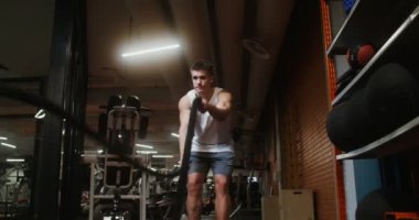 Genç adam modern jimnastik salonunda dövüş ipleri kullanıyor.