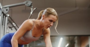 Genç bir kadın spor salonunda dambıllarla çalışmaya başlıyor.