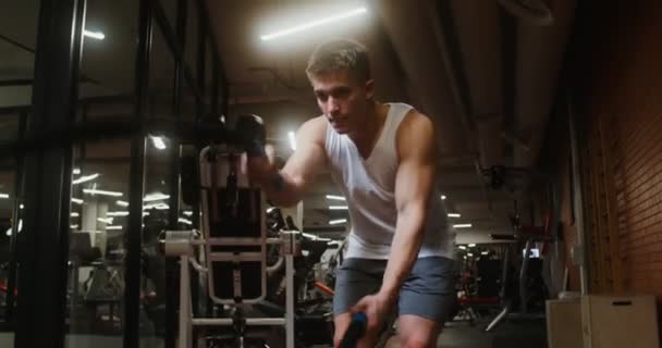 Mladý muž používá bojová lana během silového tréninku v moderní tělocvičně