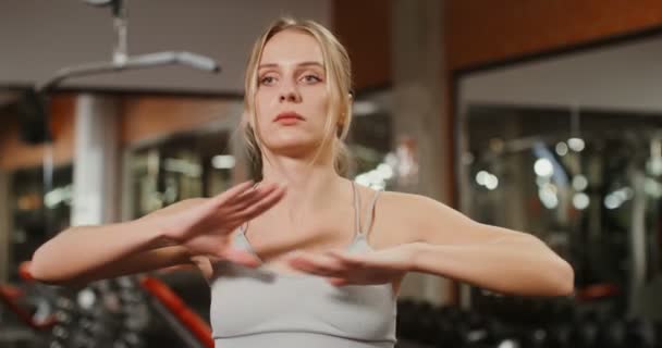 Женщина делает разминку перед началом занятий по тренажерам в спортзале — стоковое видео