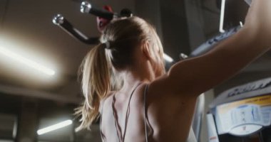 Genç bir kadın spor salonundaki simülatörde çekilmiş, yakın plan.
