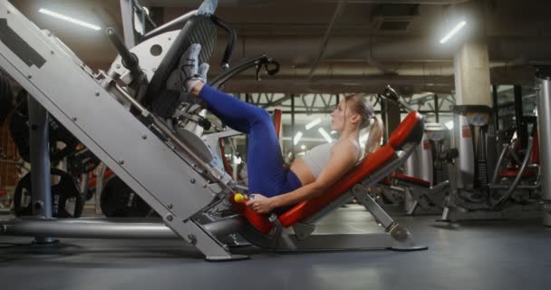 Uma mulher fazendo exercícios para as pernas na máquina de exercícios — Vídeo de Stock
