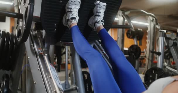 Una donna che fa esercizi per le gambe sulla macchina esercizio — Video Stock