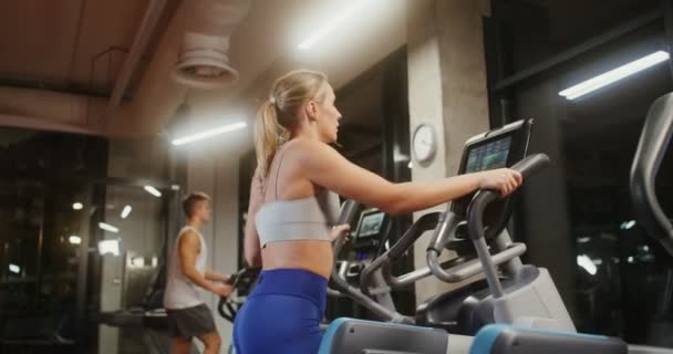 Young people exercise on an ellipse in a well-equipped indoor gym — Stock Video