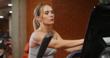 Bir kadın kapalı spor salonunda bir elips içinde, yakın plan.