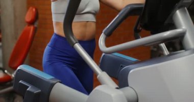 Bir kadın kapalı spor salonunda bir elips içinde, yakın plan.