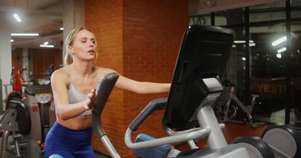 Una mujer se dedica a una elipse en un gimnasio cubierto, Primer plano — Vídeo de stock