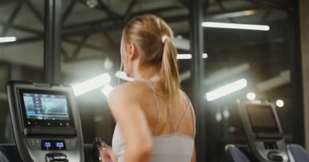 Jonge vrouw loopt op een loopband trainen van de sportschool — Stockvideo