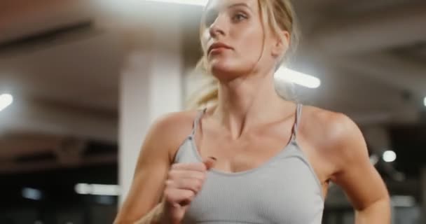 Genç bir kadın spor salonunda koşu bandında koşuyor. — Stok video