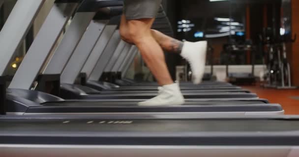 En ung man med europeiskt utseende springer på löpband i gymmet — Stockvideo