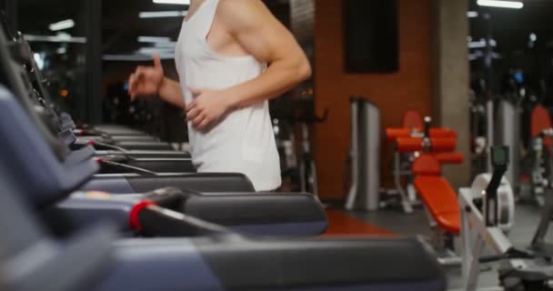 Mladý muž evropského vzhledu na běžícím pásu v tělocvičně — Stock video