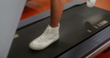 Avrupa görünümlü genç bir adam spor salonunda koşu bandında koşuyor.