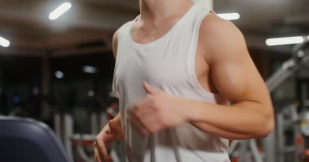 A young man of European appearance running on a treadmill in the gym — Stock Video