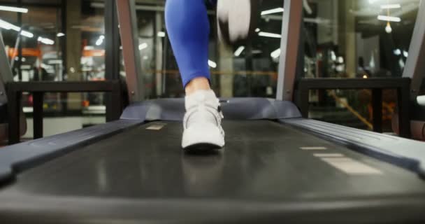 Žena běží na běžícím pásu, cvičí v tělocvičně, zblízka ženských nohou — Stock video