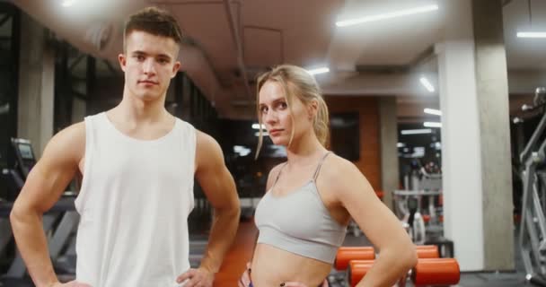 Junge Männer und Frauen blicken in die Kamera und legen im Fitnessstudio ihre Hände an den Gürtel — Stockvideo