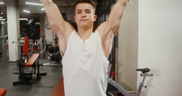 Front view of a young man doing pull-ups on the simulator in a modern gym — Stockvideo