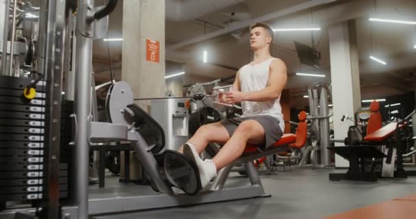 Un giovane uomo è impegnato in una macchina da ginnastica, scuotendo i muscoli del petto — Video Stock