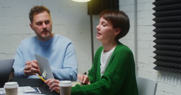 Jovens colegas trabalham em equipe, usando laptop e se comunicando, sentados no escritório — Vídeo de Stock