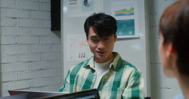 Az ázsiai külsejű fiatalember kommunikál az irodában ülő kollégáival. — Stock videók