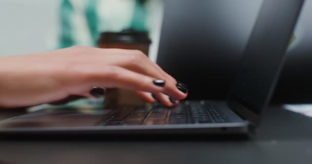 オフィスに座っている間、ノートパソコンのキーボードに入力する女性の手のクローズアップショット — ストック動画