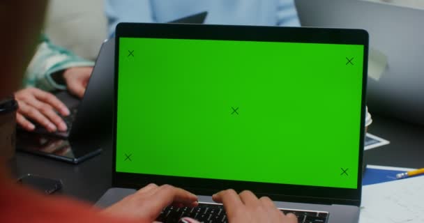 Seorang wanita menggunakan laptop dengan layar hijau sambil duduk di samping rekan-rekannya — Stok Video
