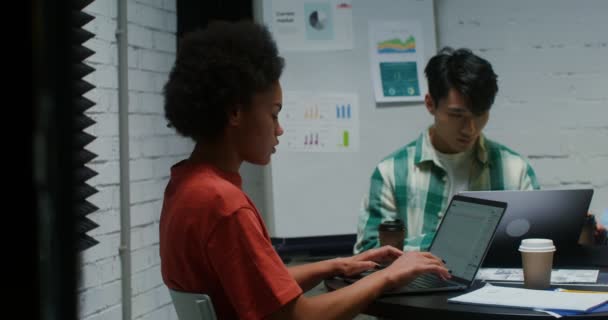Jóvenes colegas trabajan en equipo, usando laptop y comunicándose, sentados en la oficina — Vídeo de stock