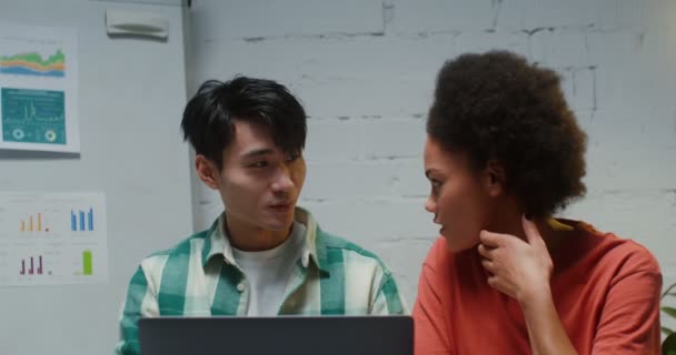 Egy pár dolgozik egy helyen, laptopon ülnek egy irodában, és élvezik egymást. — Stock videók