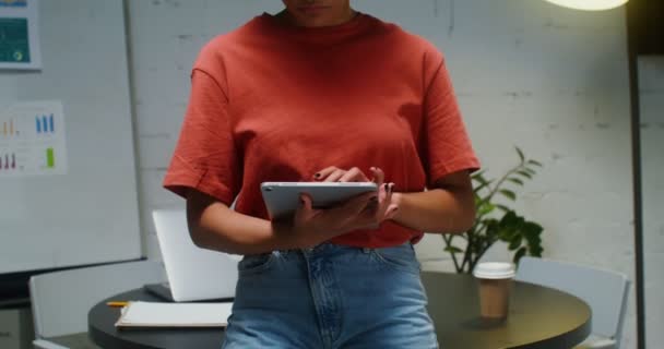 Mladá žena používá digitální tablet v kanceláři, pak se dívá do kamery — Stock video