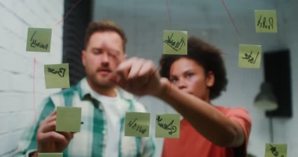 A young man and woman are planning in the office, drawing on a glass board — Video Stock