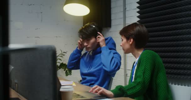 Um jovem e uma mulher conversando durante o dia de trabalho, sentados na mesma mesa — Vídeo de Stock
