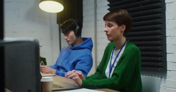 Um jovem e uma mulher trabalhando em um projeto comum e usando laptops — Vídeo de Stock
