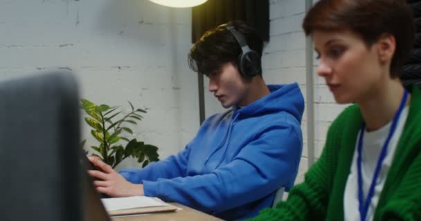 Un hombre y una mujer jóvenes que trabajan en un proyecto común y utilizan computadoras portátiles — Vídeos de Stock