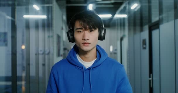Un uomo asiatico con uno sguardo serio guarda nella fotocamera, in piedi in ufficio — Video Stock